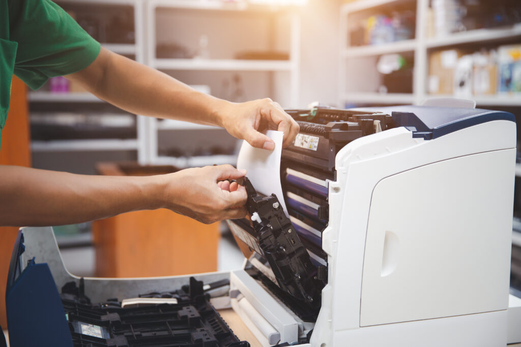 Technician servicing a high-quality printer, emphasizing efficient construction drawing printing services for projects in Warminster.